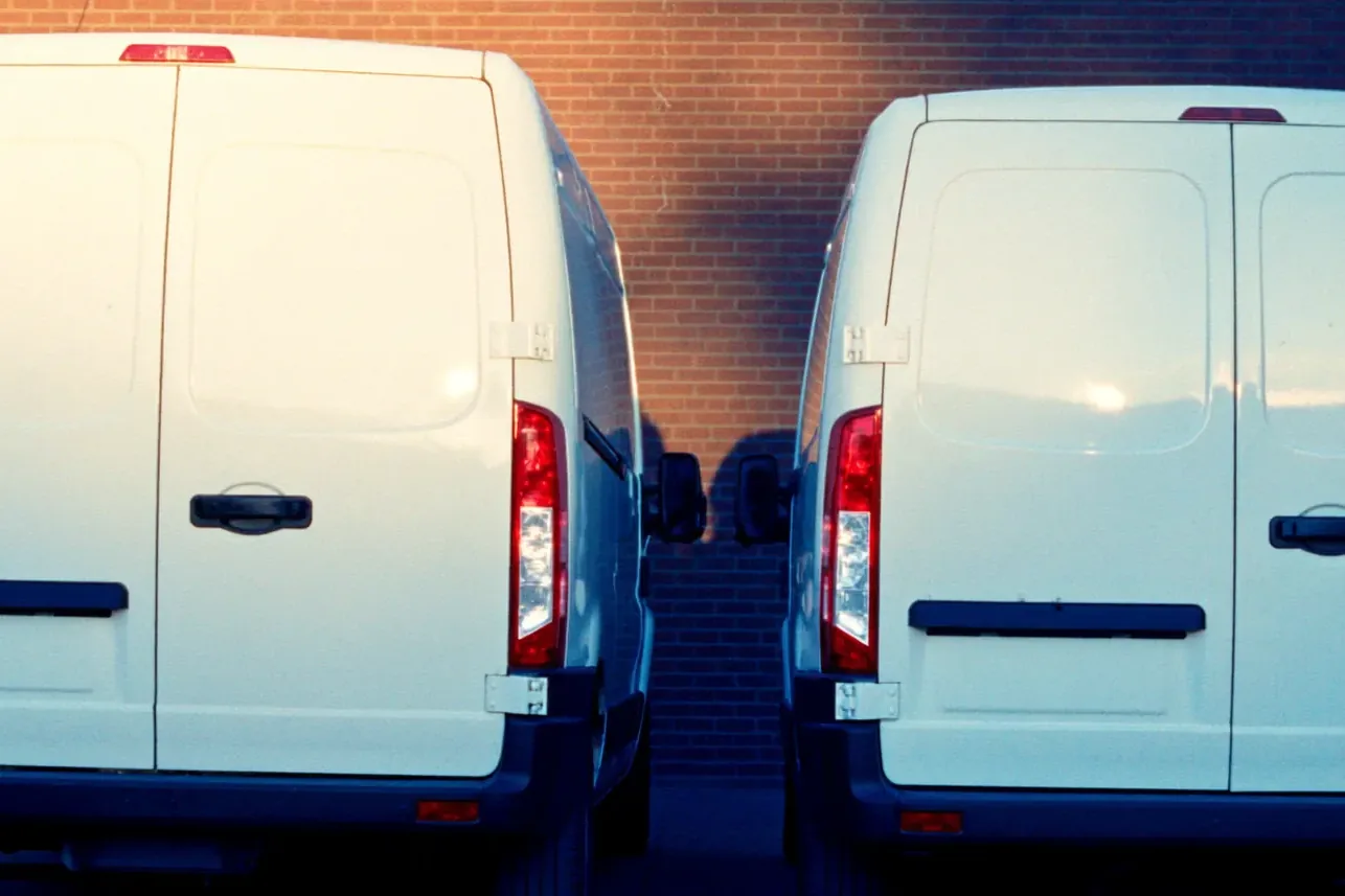 Two white A & A Twin Glass mobile service vans parked side by side against a brick wall in Newark.